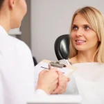 Dentist consulting with smiling patient about root canal treatment options in modern dental office