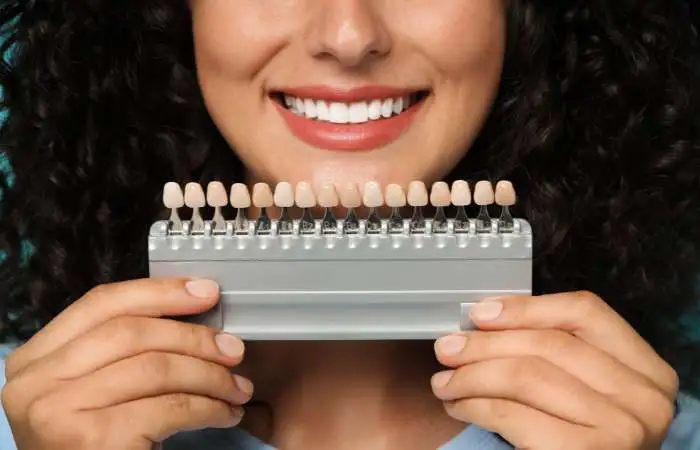 Woman holding tooth shade guide for porcelain veneers Upland color matching consultation at cosmetic dentistry office